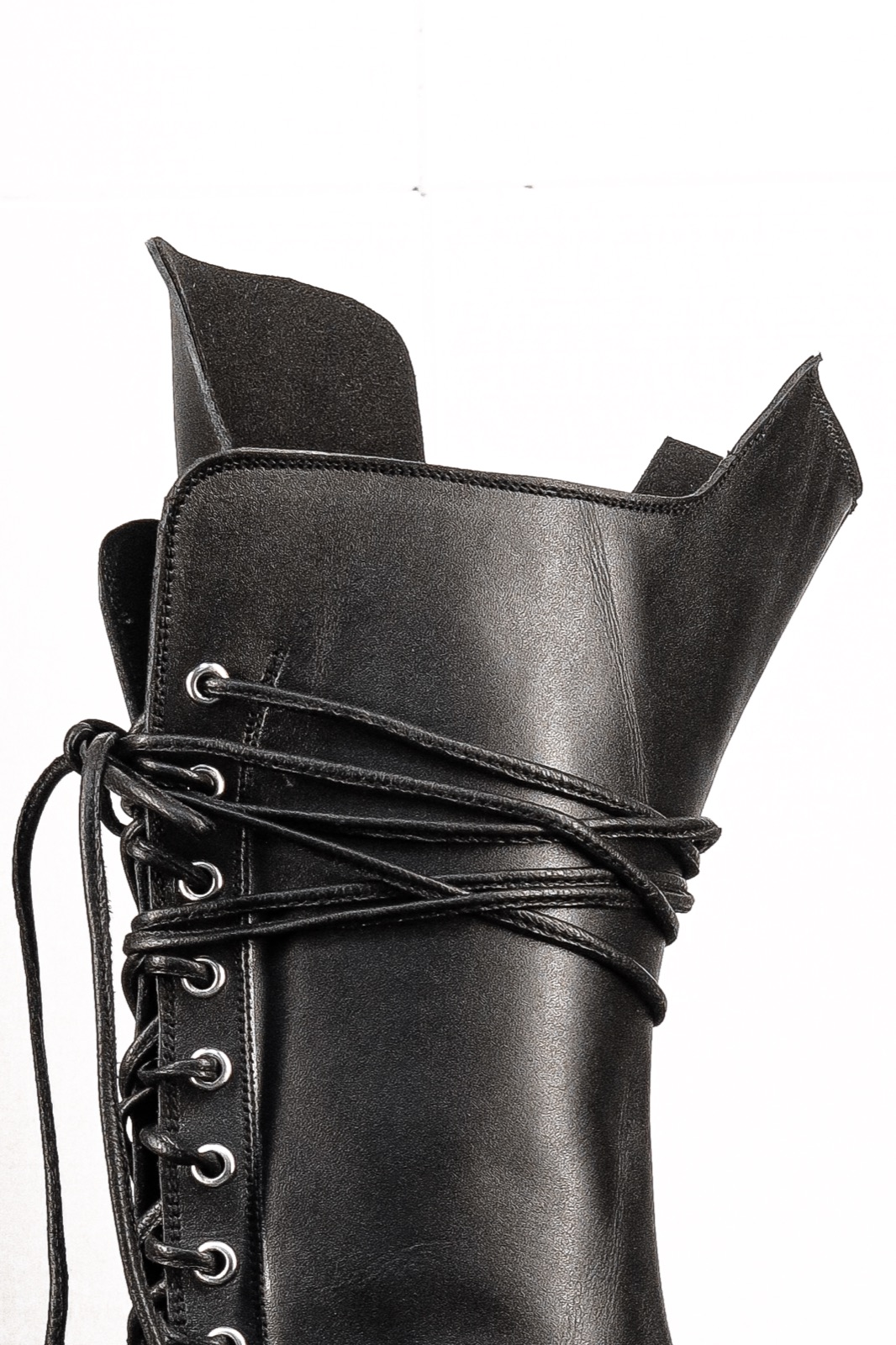 Close-up of the CRÜZØR PRAVAHA boot's leather lace wrapping the shaft, with the upper-lip collar flared open